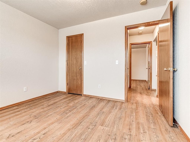 spare room featuring light hardwood / wood-style floors and a textured ceiling