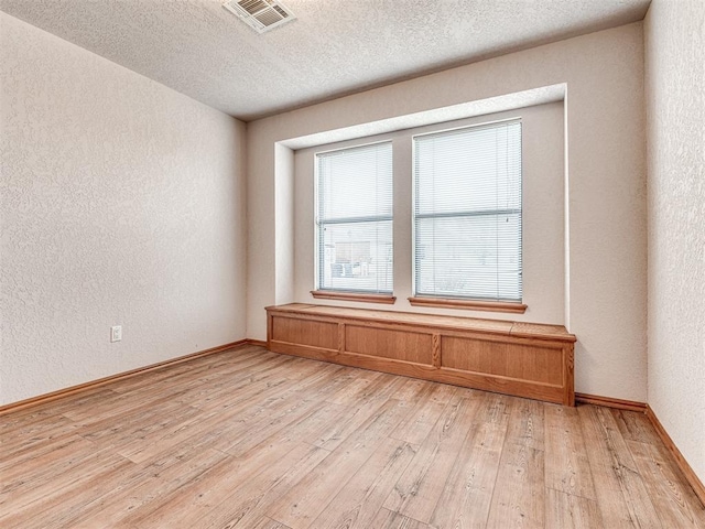 unfurnished room featuring a textured ceiling and light hardwood / wood-style floors