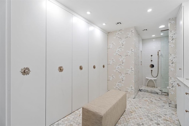 bathroom with tiled shower and tile patterned flooring