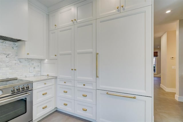 kitchen featuring high end stove, white cabinetry, backsplash, light tile patterned floors, and light stone counters