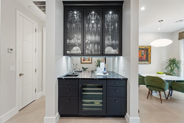 bar with sink, pendant lighting, beverage cooler, and backsplash