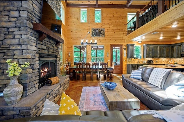 living room featuring a high ceiling, a stone fireplace, and a healthy amount of sunlight