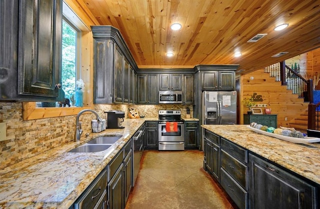 kitchen featuring sink, wood ceiling, appliances with stainless steel finishes, light stone counters, and wood walls