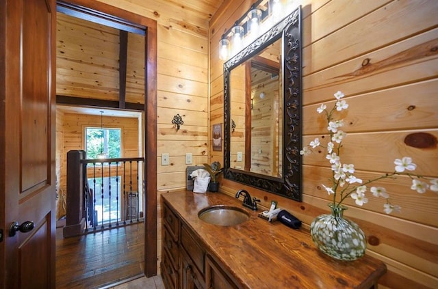 bathroom with tile patterned flooring, vanity, wood ceiling, and wood walls