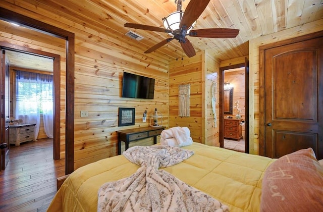 bedroom featuring ensuite bathroom, wood ceiling, wooden walls, ceiling fan, and hardwood / wood-style floors