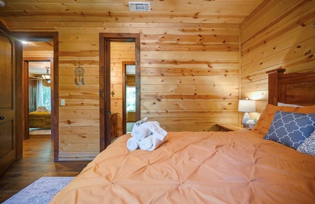 bedroom with dark hardwood / wood-style floors and wood walls