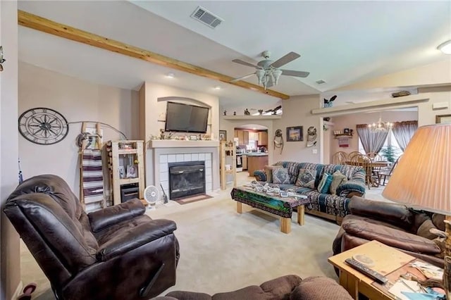 living room with a tiled fireplace, ceiling fan with notable chandelier, lofted ceiling with beams, and carpet flooring