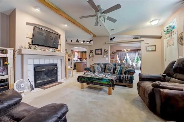 carpeted living room featuring vaulted ceiling with beams, ceiling fan with notable chandelier, and a tile fireplace