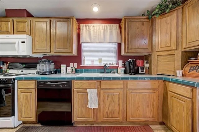 kitchen featuring range, tile counters, dishwasher, and sink