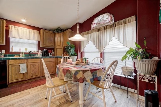 dining area featuring lofted ceiling, sink, and light hardwood / wood-style floors