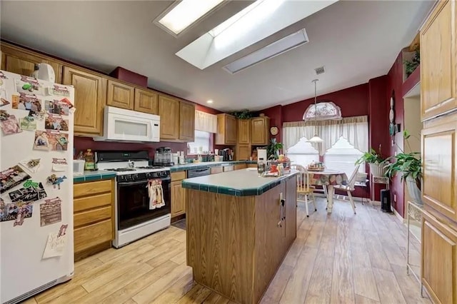 kitchen with pendant lighting, white appliances, tile countertops, and a kitchen island