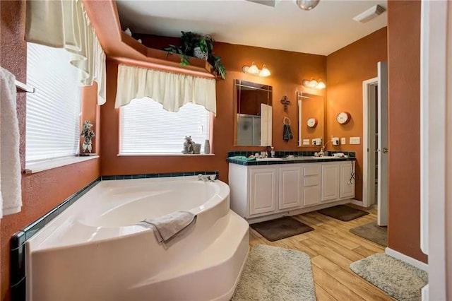 bathroom with a tub to relax in, wood-type flooring, and vanity