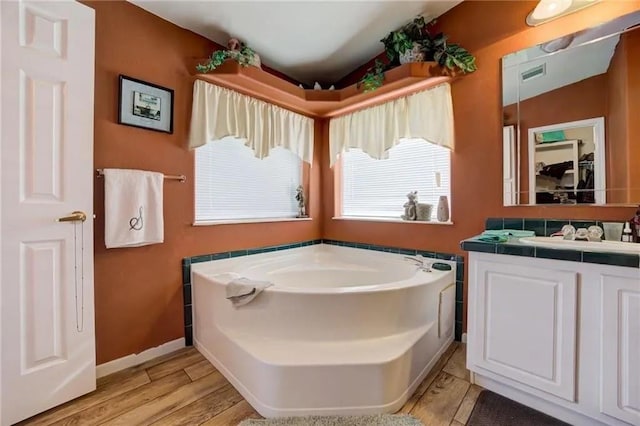 bathroom with hardwood / wood-style flooring, vanity, and a bathtub