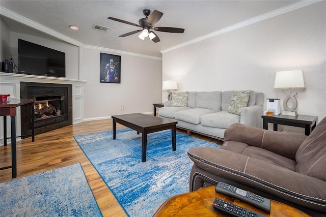 living room with crown molding, wood-type flooring, and ceiling fan