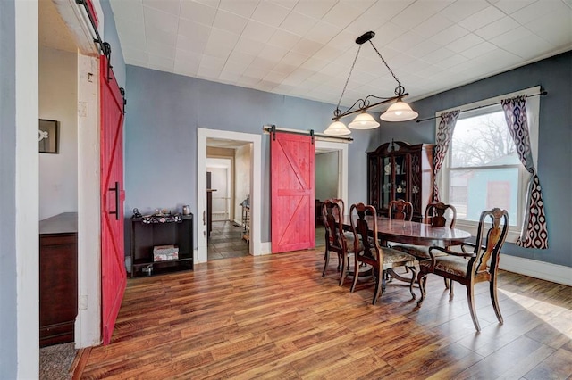 dining space featuring wood-type flooring and a barn door