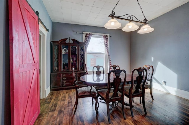 dining room with dark hardwood / wood-style floors and a barn door