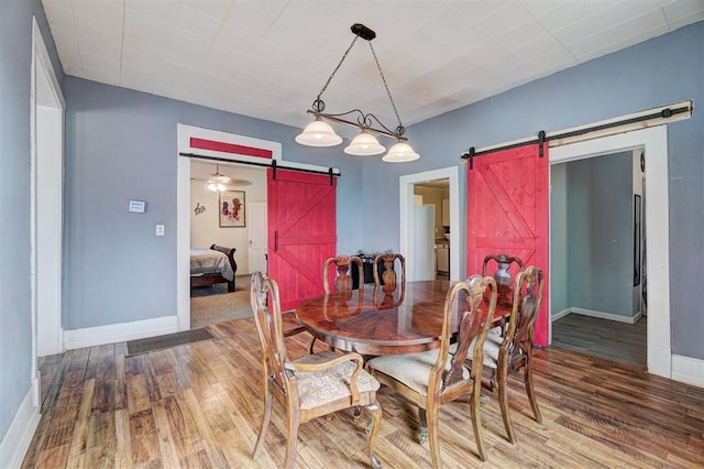 dining area with wood-type flooring and a barn door