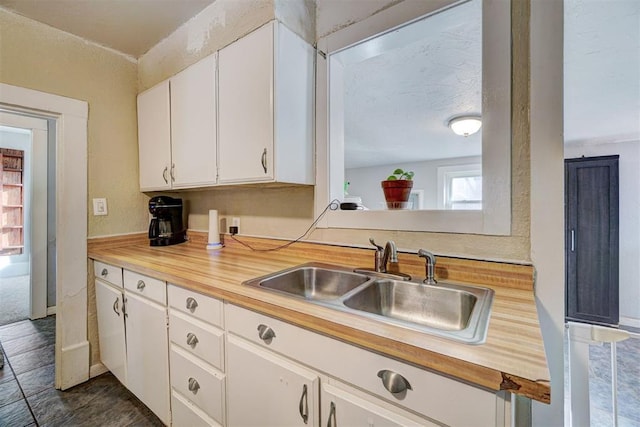 kitchen with sink, a textured ceiling, and white cabinets