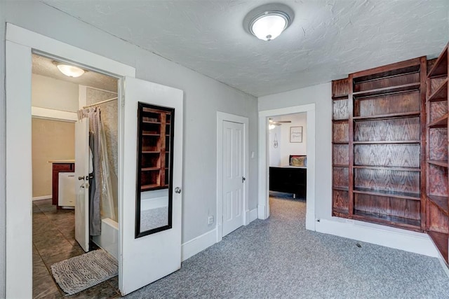 hallway with dark carpet and a textured ceiling