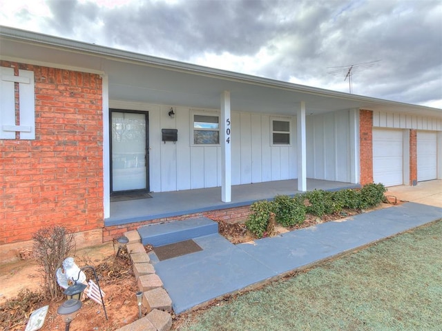 view of exterior entry with a garage and covered porch