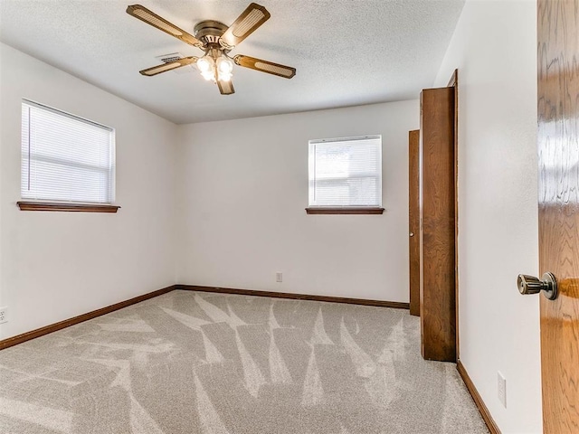 empty room featuring ceiling fan, light colored carpet, and a textured ceiling