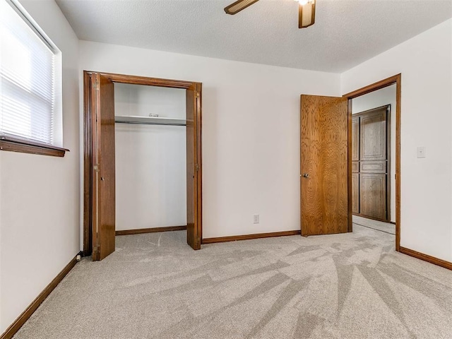 unfurnished bedroom with light carpet, a textured ceiling, ceiling fan, and a closet