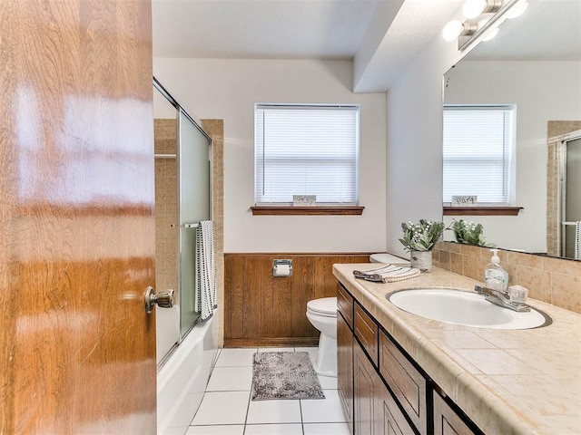 full bathroom featuring enclosed tub / shower combo, tile patterned flooring, wooden walls, vanity, and toilet