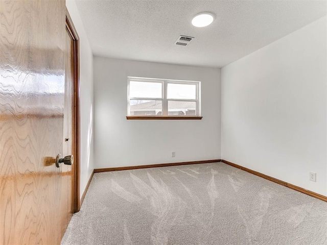 carpeted empty room with a textured ceiling