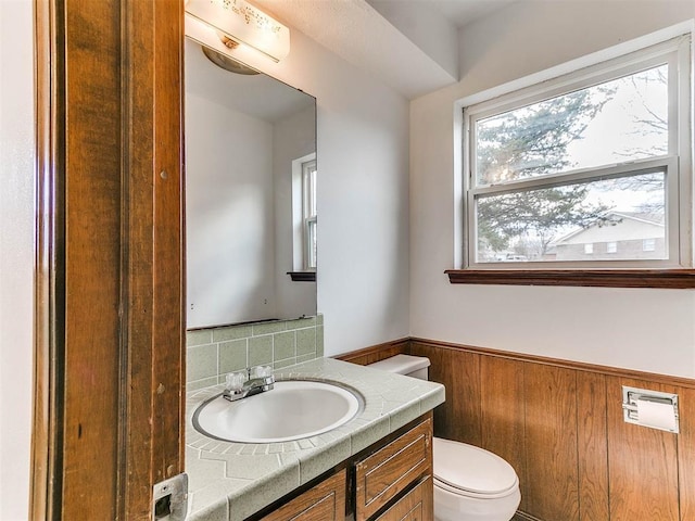 bathroom with vanity, wooden walls, and toilet