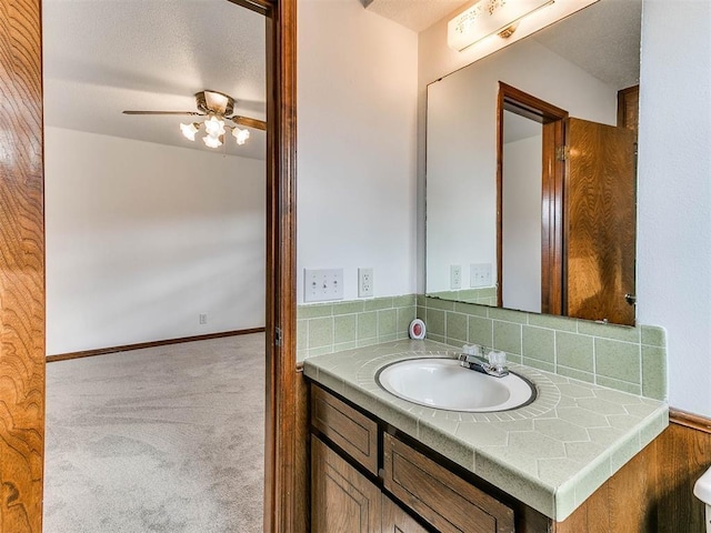 bathroom featuring ceiling fan, vanity, and decorative backsplash