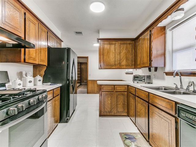 kitchen featuring black refrigerator, sink, and stainless steel gas range oven