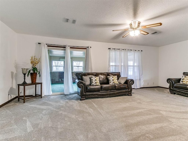 living room with ceiling fan, a textured ceiling, and carpet flooring