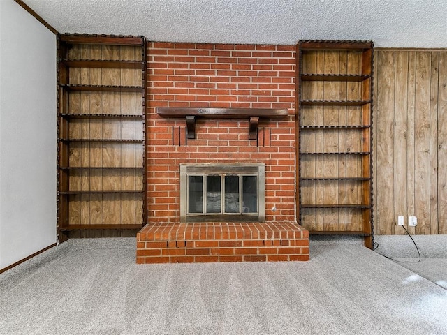 unfurnished living room with a fireplace, wooden walls, a textured ceiling, and carpet