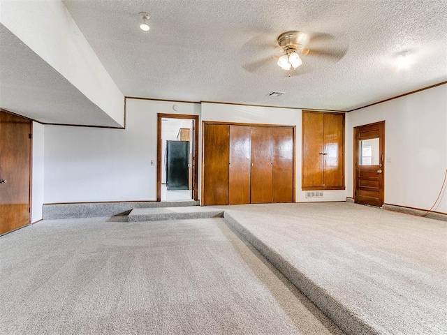 carpeted spare room featuring ceiling fan and a textured ceiling