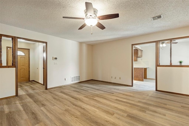 empty room with ceiling fan, a textured ceiling, and light hardwood / wood-style flooring