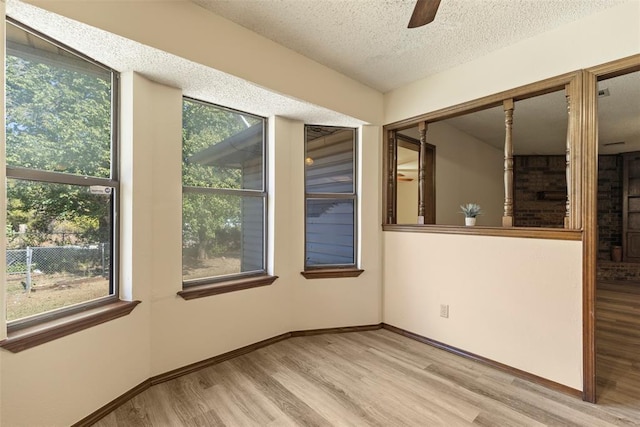 empty room with ceiling fan, light hardwood / wood-style floors, and a textured ceiling