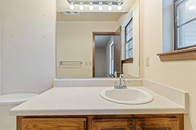 bathroom featuring vanity, plenty of natural light, and toilet