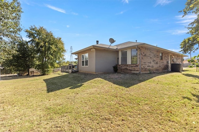 rear view of property with central AC unit and a yard