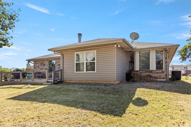 rear view of house featuring cooling unit, a wooden deck, and a lawn