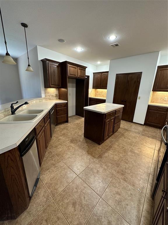 kitchen featuring tasteful backsplash, sink, decorative light fixtures, and dishwasher