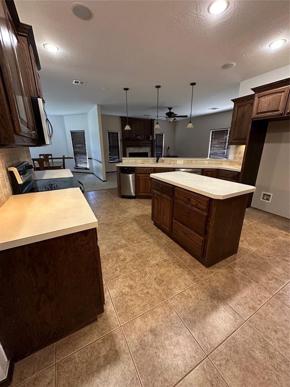 kitchen featuring tasteful backsplash, appliances with stainless steel finishes, decorative light fixtures, and kitchen peninsula