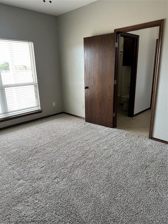 unfurnished bedroom with ensuite bathroom and light carpet