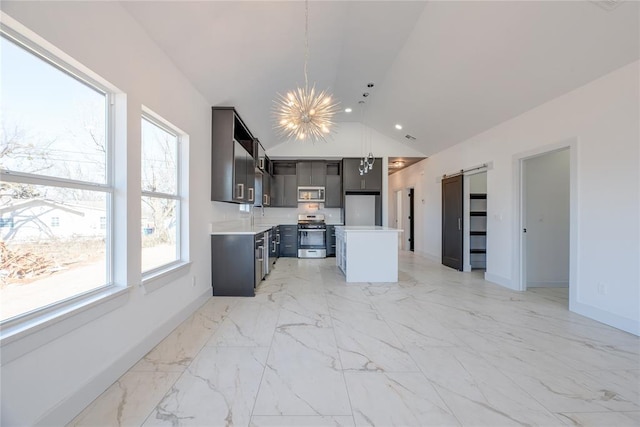 kitchen with lofted ceiling, an inviting chandelier, appliances with stainless steel finishes, pendant lighting, and a barn door