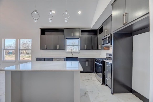 kitchen featuring stainless steel appliances, decorative light fixtures, a center island, and sink