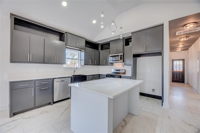 kitchen with vaulted ceiling, a kitchen island, appliances with stainless steel finishes, sink, and gray cabinetry