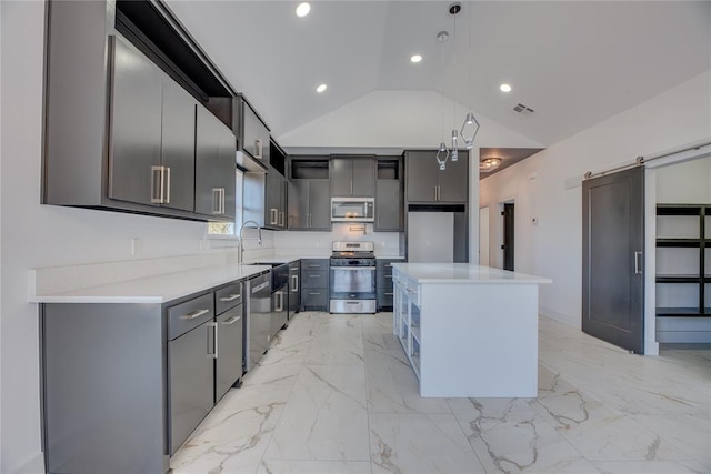 kitchen featuring appliances with stainless steel finishes, gray cabinetry, hanging light fixtures, a center island, and a barn door