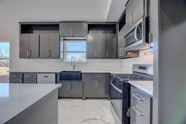 kitchen with gray cabinetry, sink, light stone counters, and stainless steel appliances