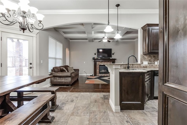 kitchen featuring coffered ceiling, sink, pendant lighting, and dark brown cabinetry