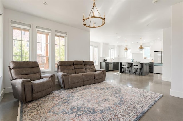 living room featuring a notable chandelier, concrete floors, and sink