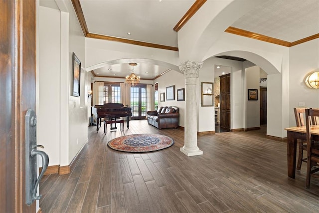 foyer entrance with ornamental molding, decorative columns, and a notable chandelier